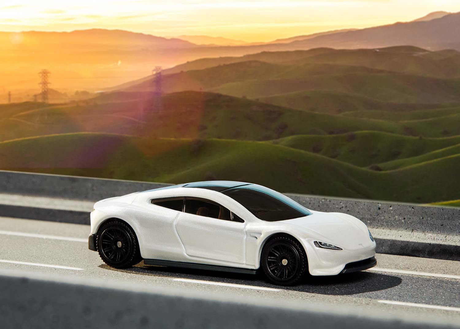 A toy car on a small road with scenery in the background