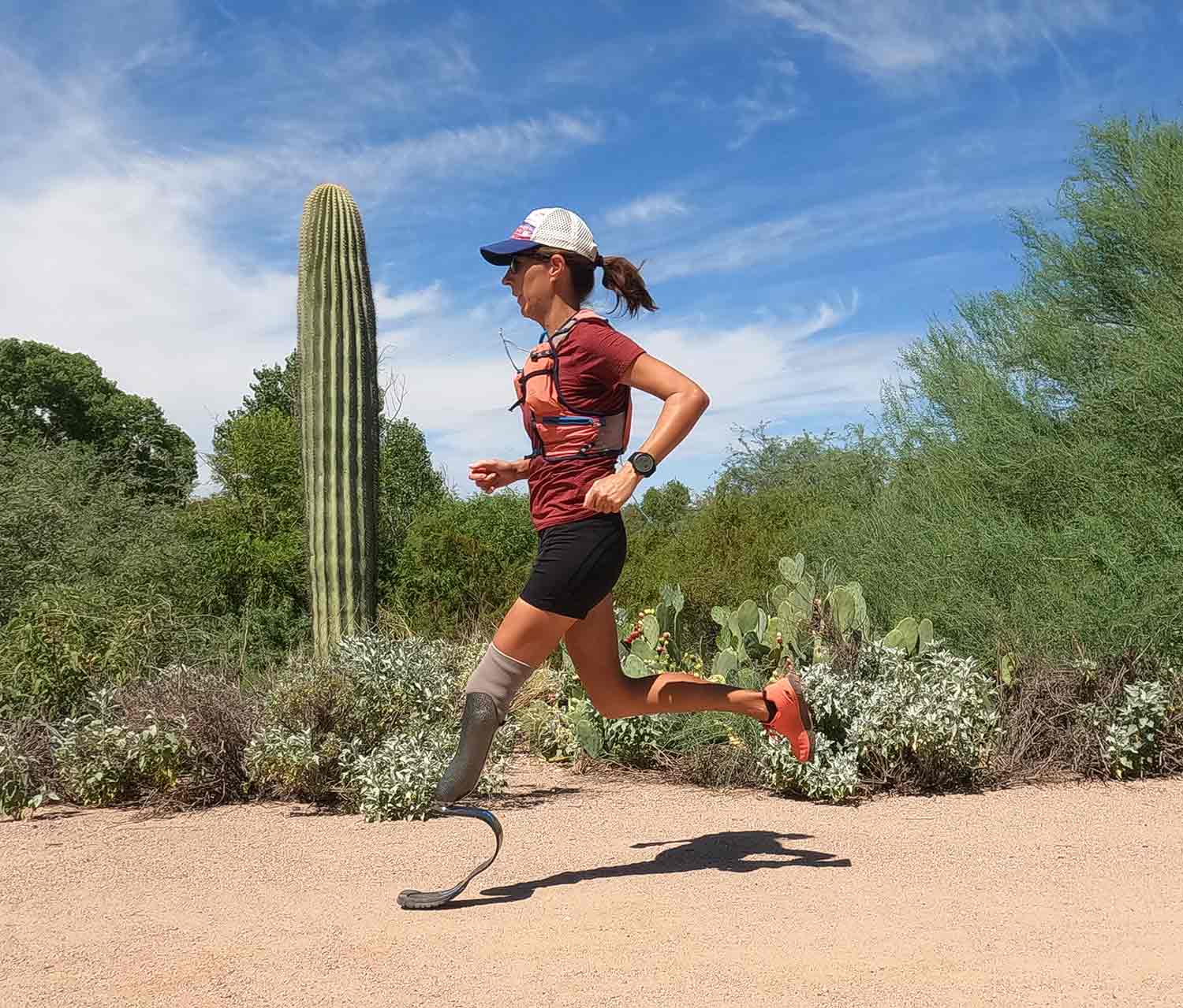 Woman with prosthetic leg running outdoors in desert terrain