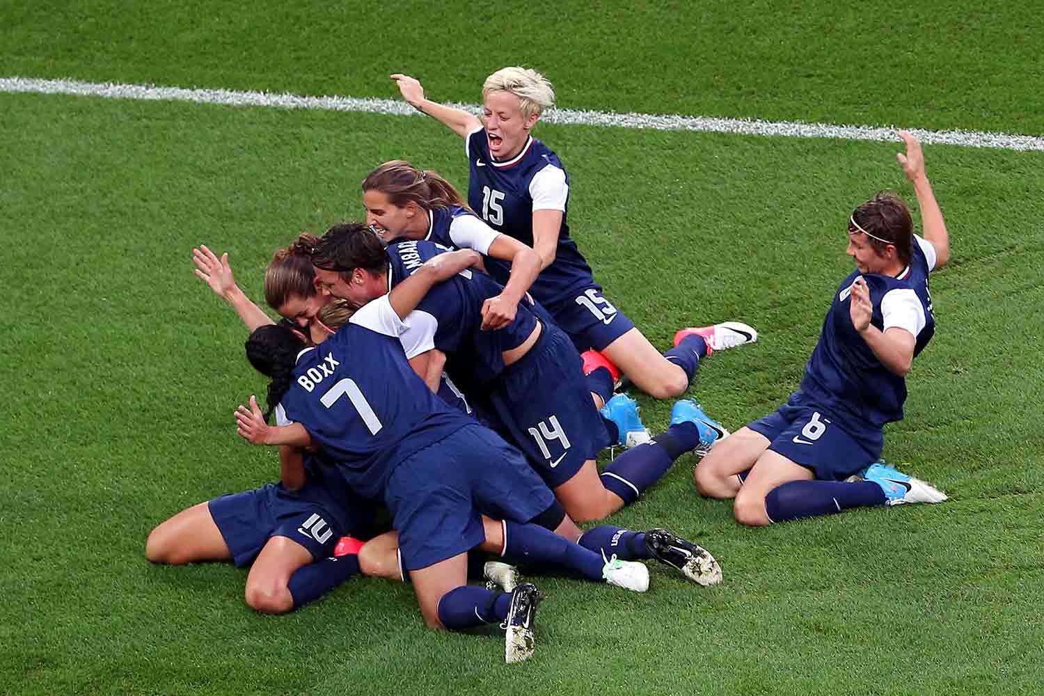 Soccer players cheering and hugging each other on a soccer field.