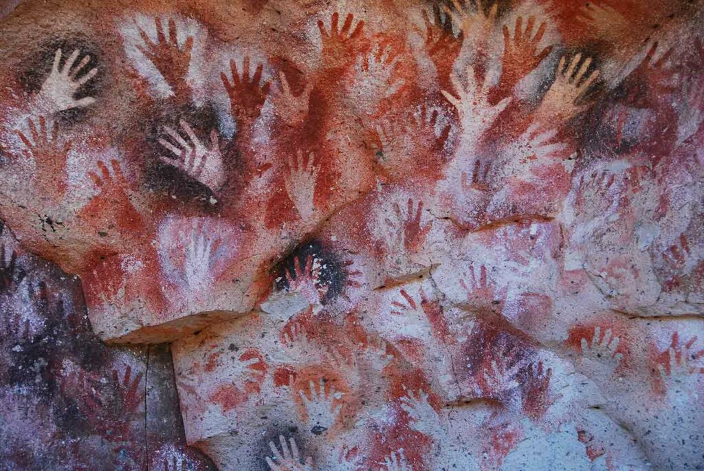 Rock wall with handprints surrounded by coloring of red and black