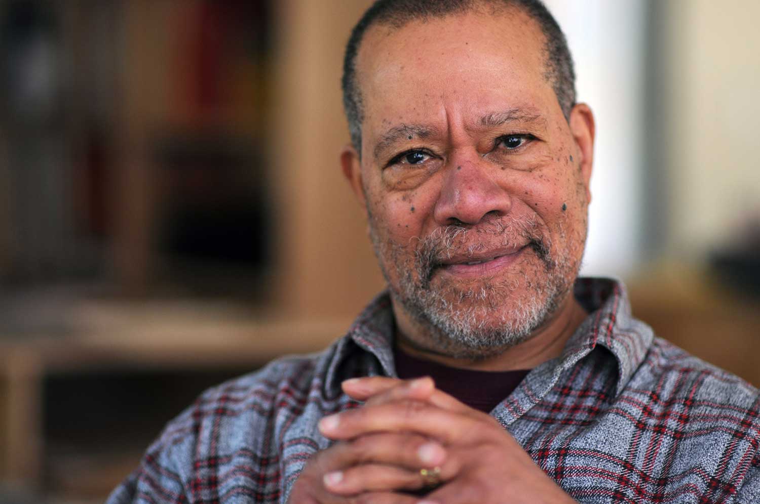 Jerry Pinkney looks into the camera with his hands folded.