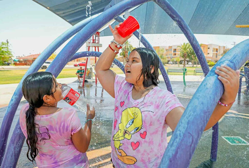 Two girls in a water park with one pouring water over her head