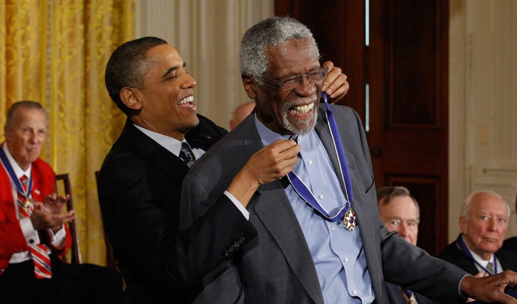 President Barack Obama laughs as he places a medal around a smiling Bill Russell’s neck.