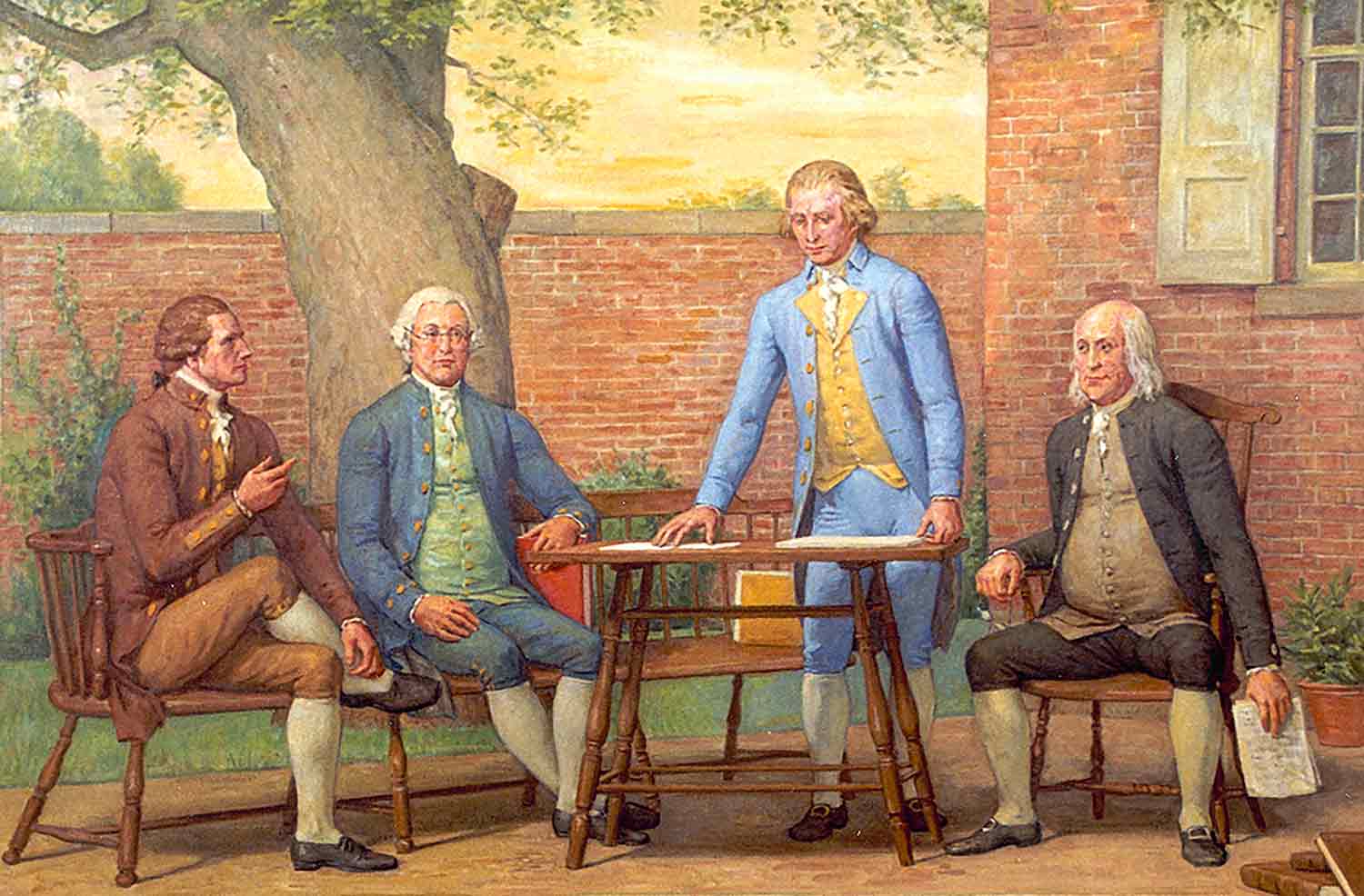 Four men in 18th century clothing sit at a table outdoors.