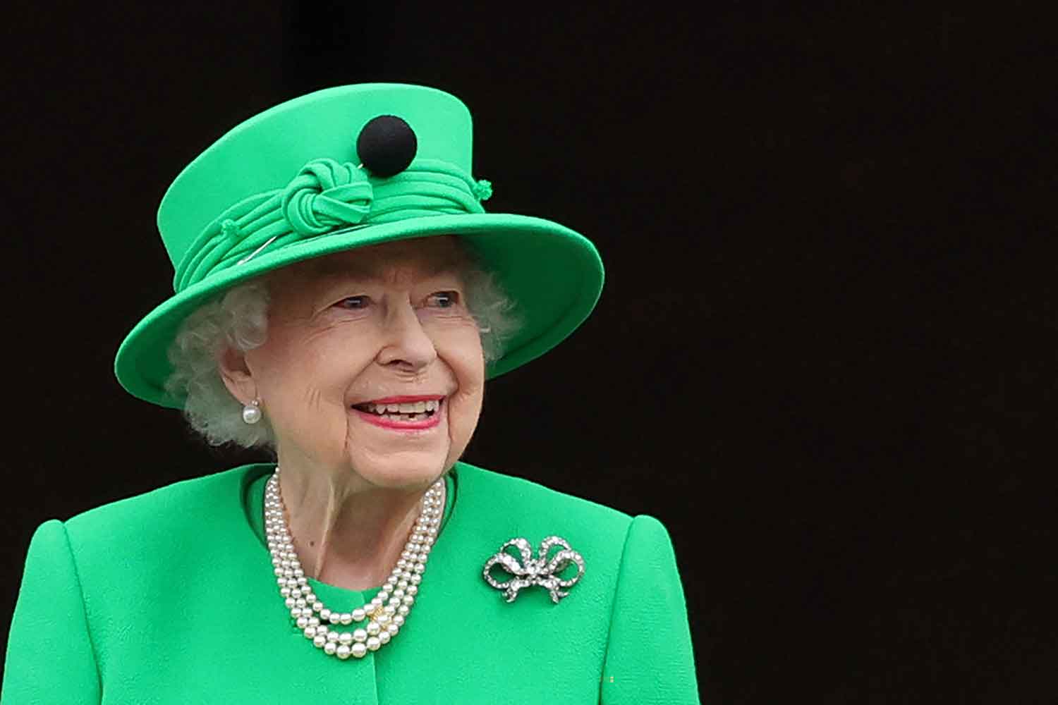Closeup of Queen Elizabeth smiling in green hat and jacket