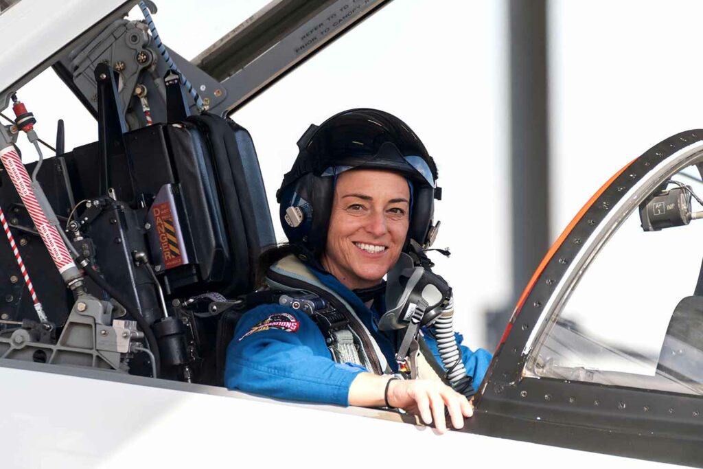 Closeup of Nicole Mann wearing flight gear and sitting in the cockpit of a training jet