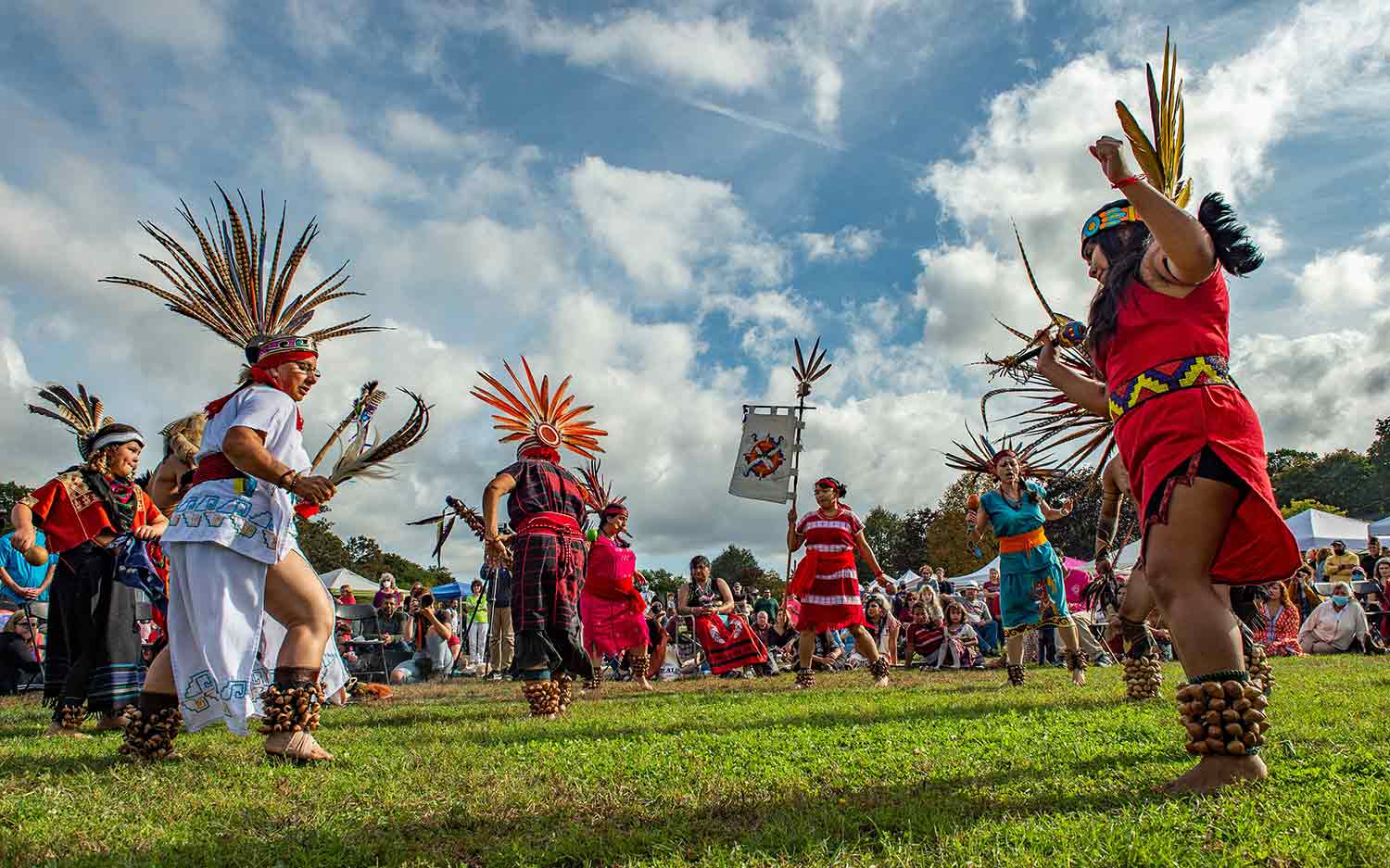People in the clothing of an American Indian nation perform a dance outdoors