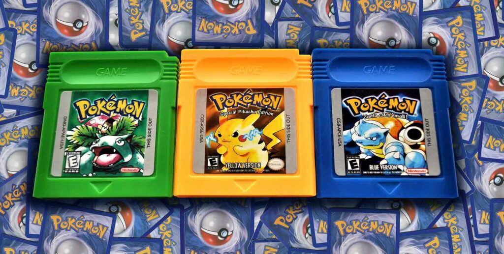 Three Pokemon game cartridges sit on a pile of Pokemon cards