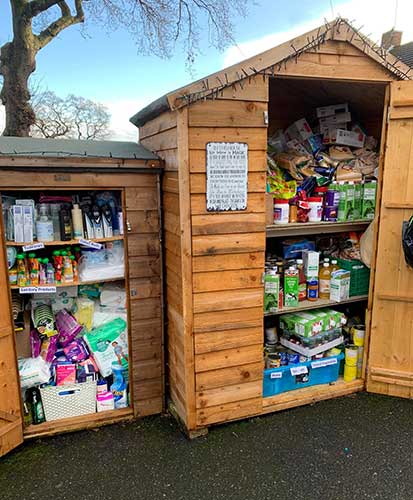 Two sheds stand next to each other. Both sheds are filled with non-perishable food items.