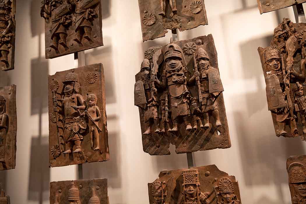 Several brass and bronze plaques carved with human figures wearing military clothing and holding weapons.