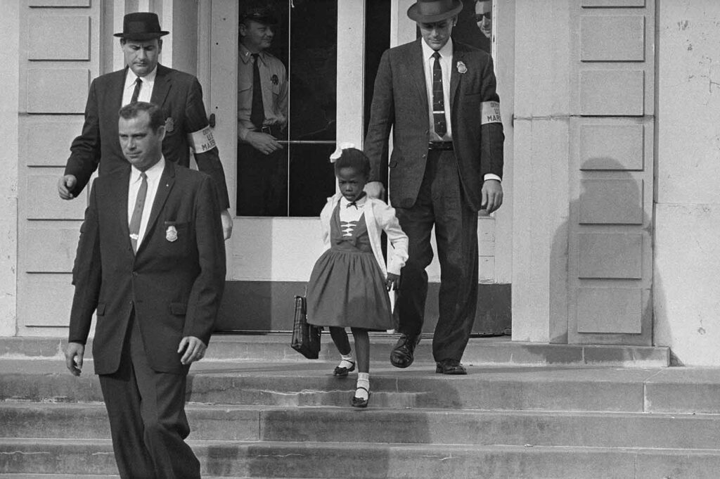 Black and white photo of a young girl and three men in suits walking down the steps of a building.