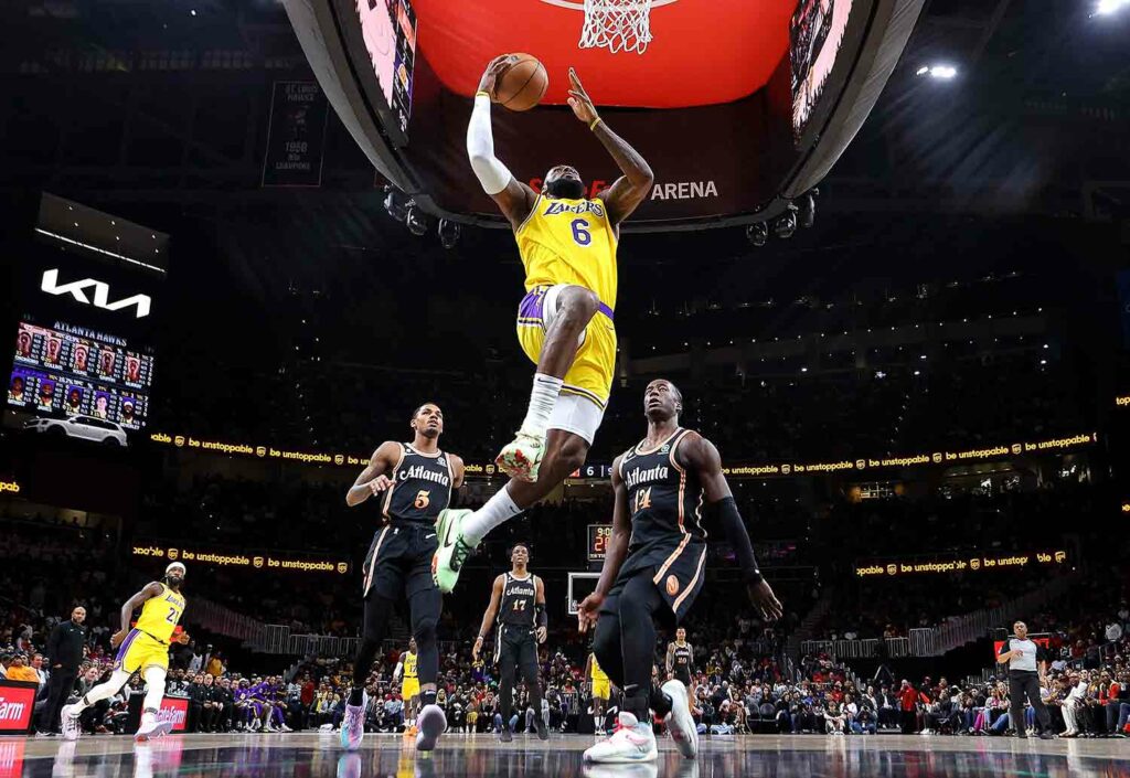 LeBron James in midair about to dunk a ball with two players in Atlanta uniforms behind him.