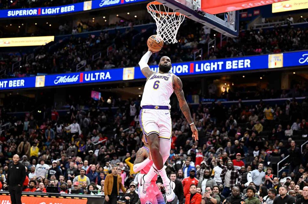 LeBron James in midair as he is about to put the ball in the basket with spectators looking on.