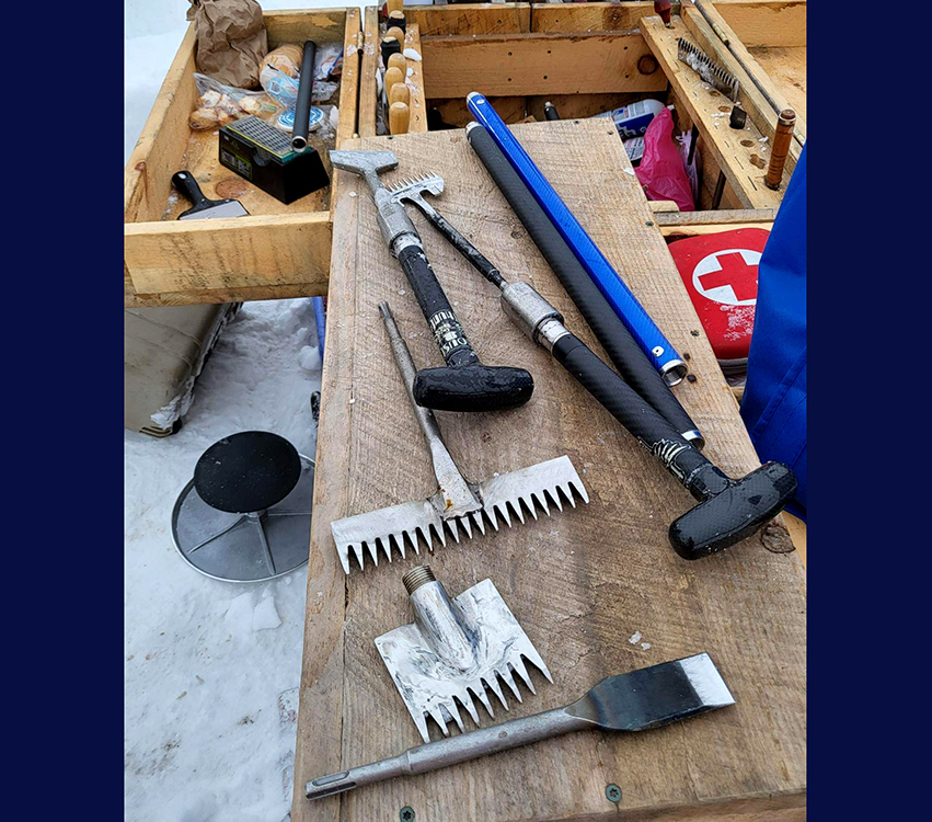 Hammers and other sculpting tools lie on a workbench that is placed outdoors