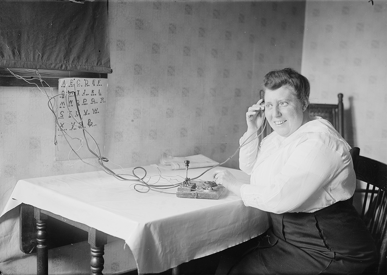 A woman uses a telegraph machine as a talk bubble states in Morse Code, “I wish there was a faster way to communicate.”