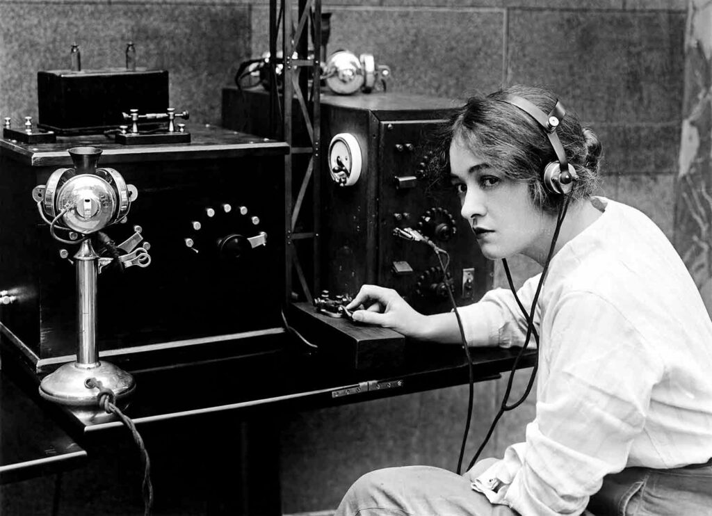 Woman from the 1920s or 1930s wearing headphones and using a telegraph machine