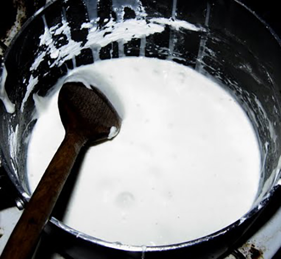 White liquid in a black pot with a wooden spoon