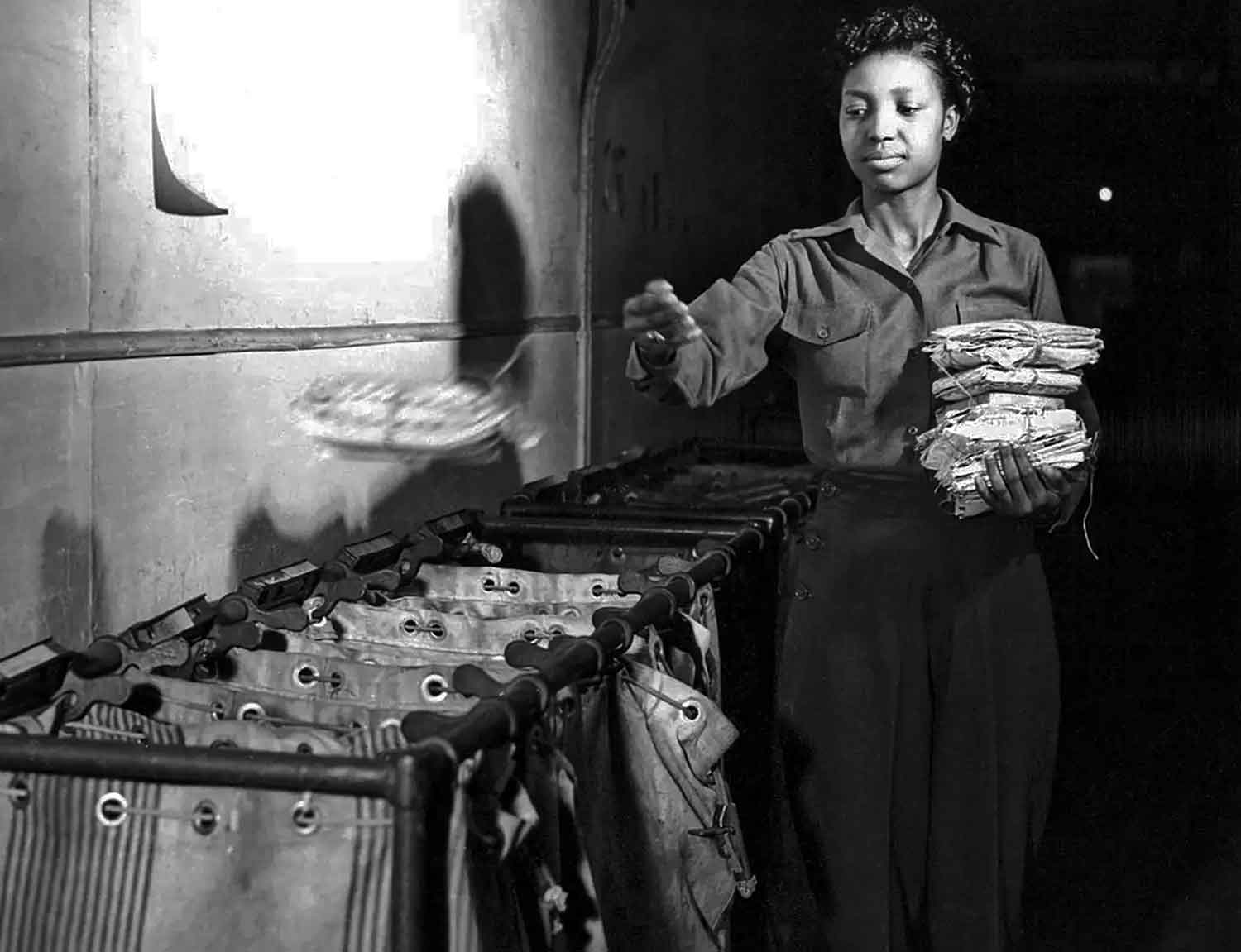 A woman throws a bound stack of mail into a bin while holding another stack of mail.