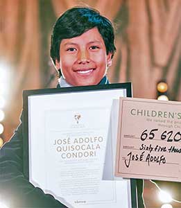 A young man smiles and holds up a framed document with a name and some text.
