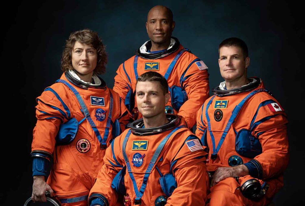 Four people pose in orange and blue spacesuits.