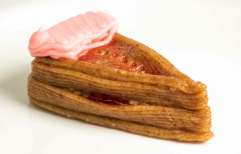 A piece of cake made up of many layers of a thick liquid that is brown and pink.