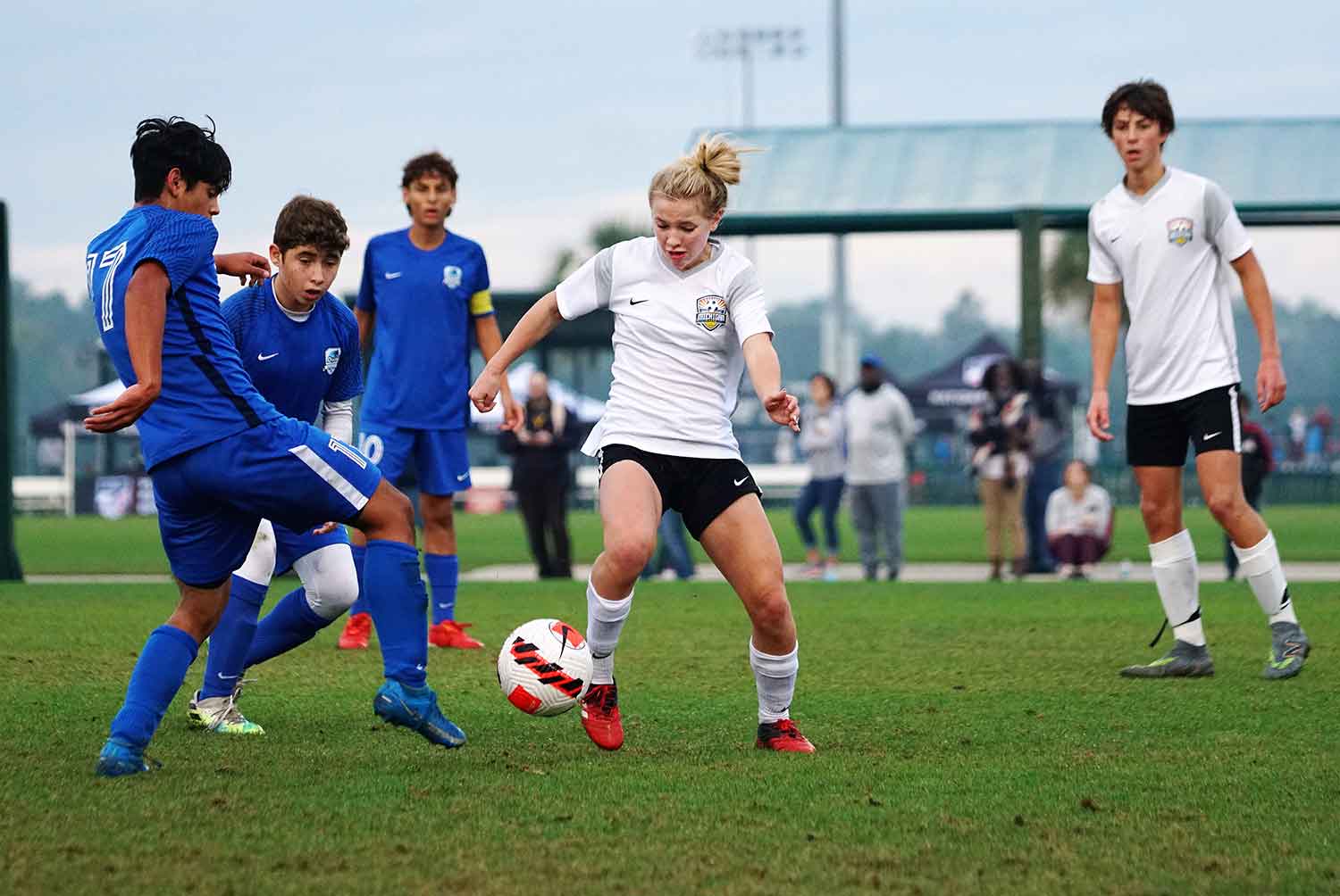 Chloe Ricketts kicking a ball on a soccer field in a match with other teens