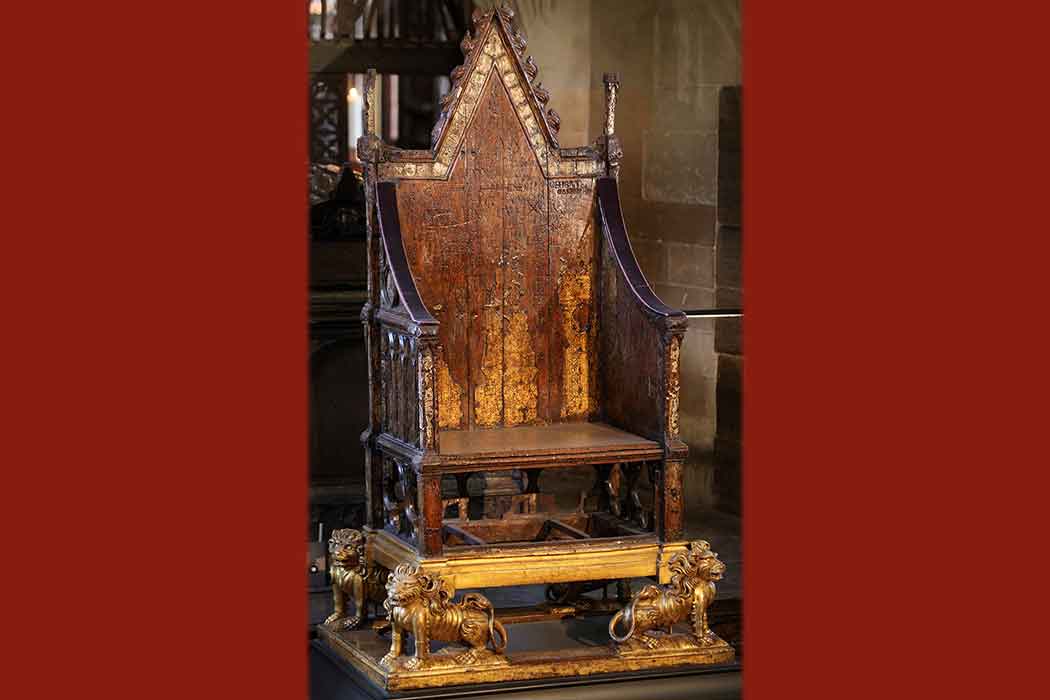 An ornate wood chair with a pointed back and a base of carved lions.