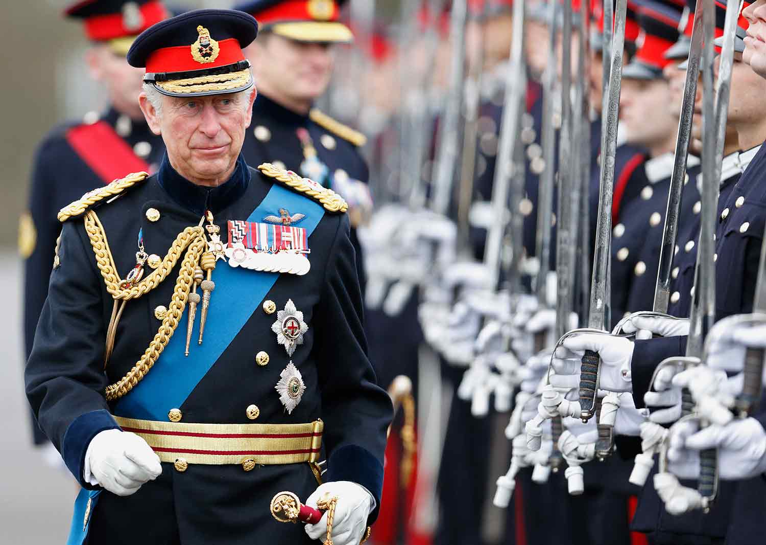 King Charles in uniform inspecting a line of soldiers holding up swords.