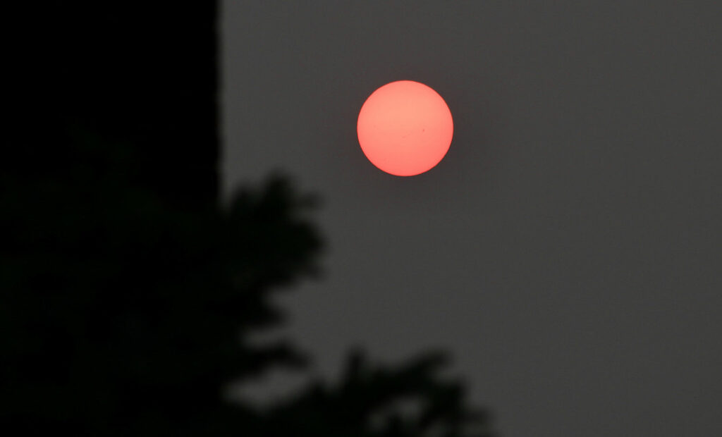 A red sun against a very dim sky.