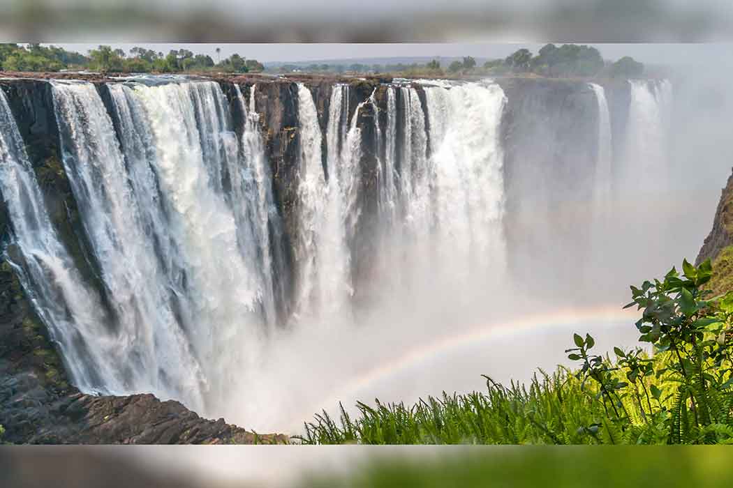 A large waterfall creates a rainbow.