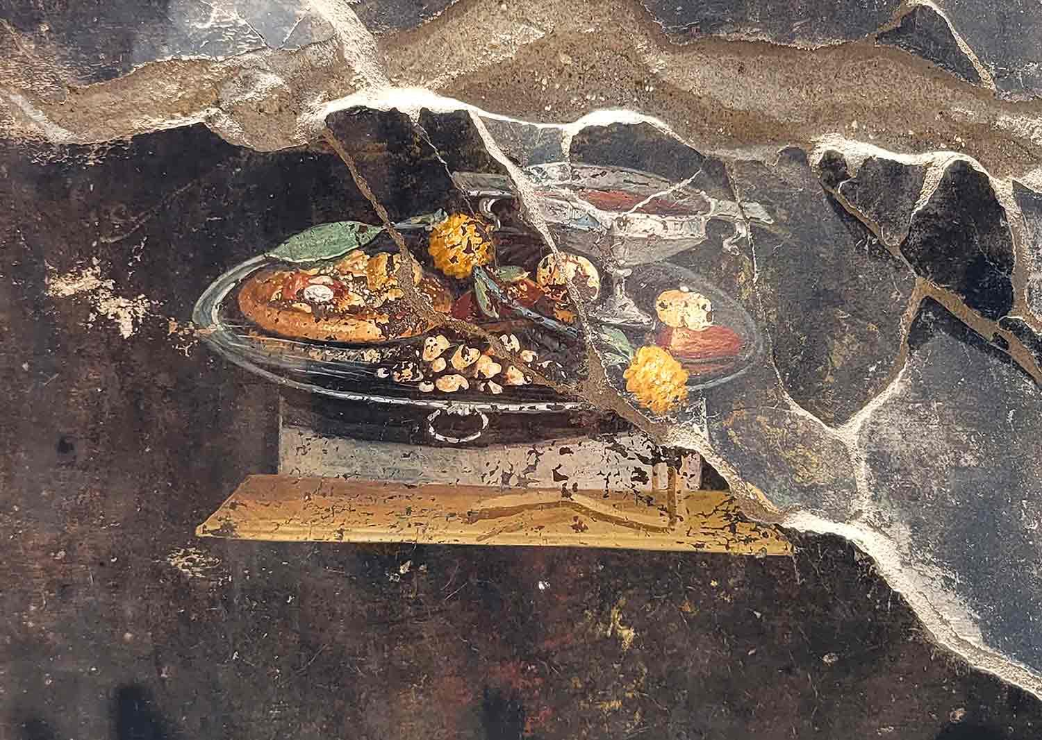 A closeup of a mural showing a tray of food, including an item that looks like a pizza.