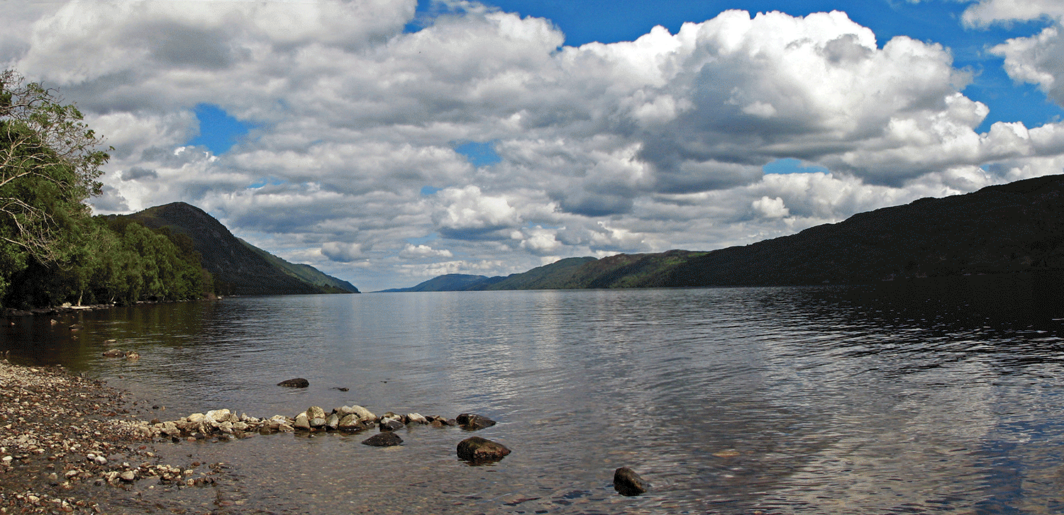 A magnifying glass passes over Loch Ness. In one spot, the outline of a monster can be seen.