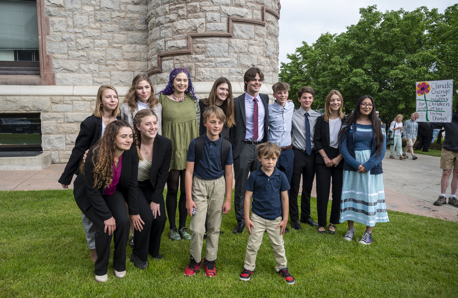 A group of children and young adults pose for a photo in front of a building.