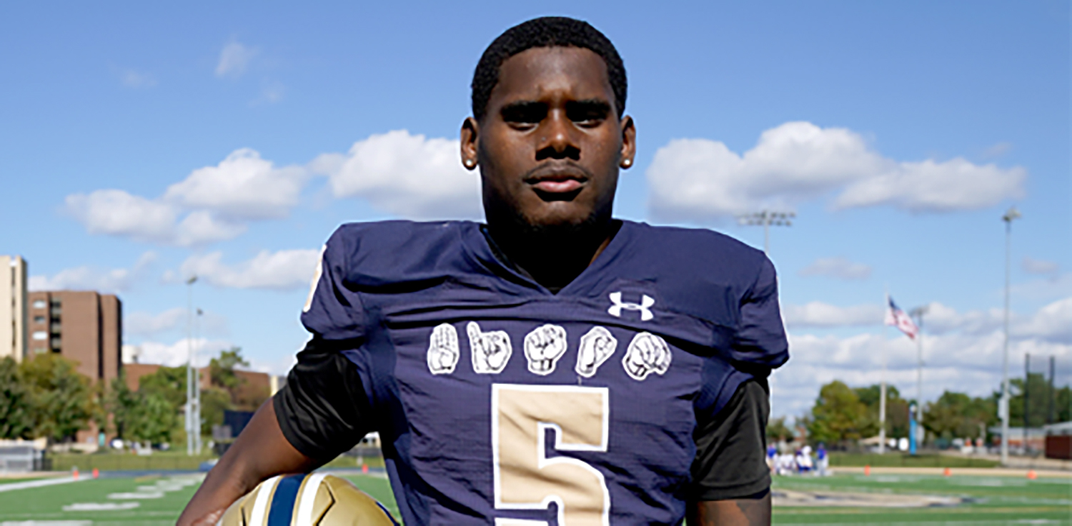 Brandon Washington poses in a jersey showing ASL signs and the number 5.