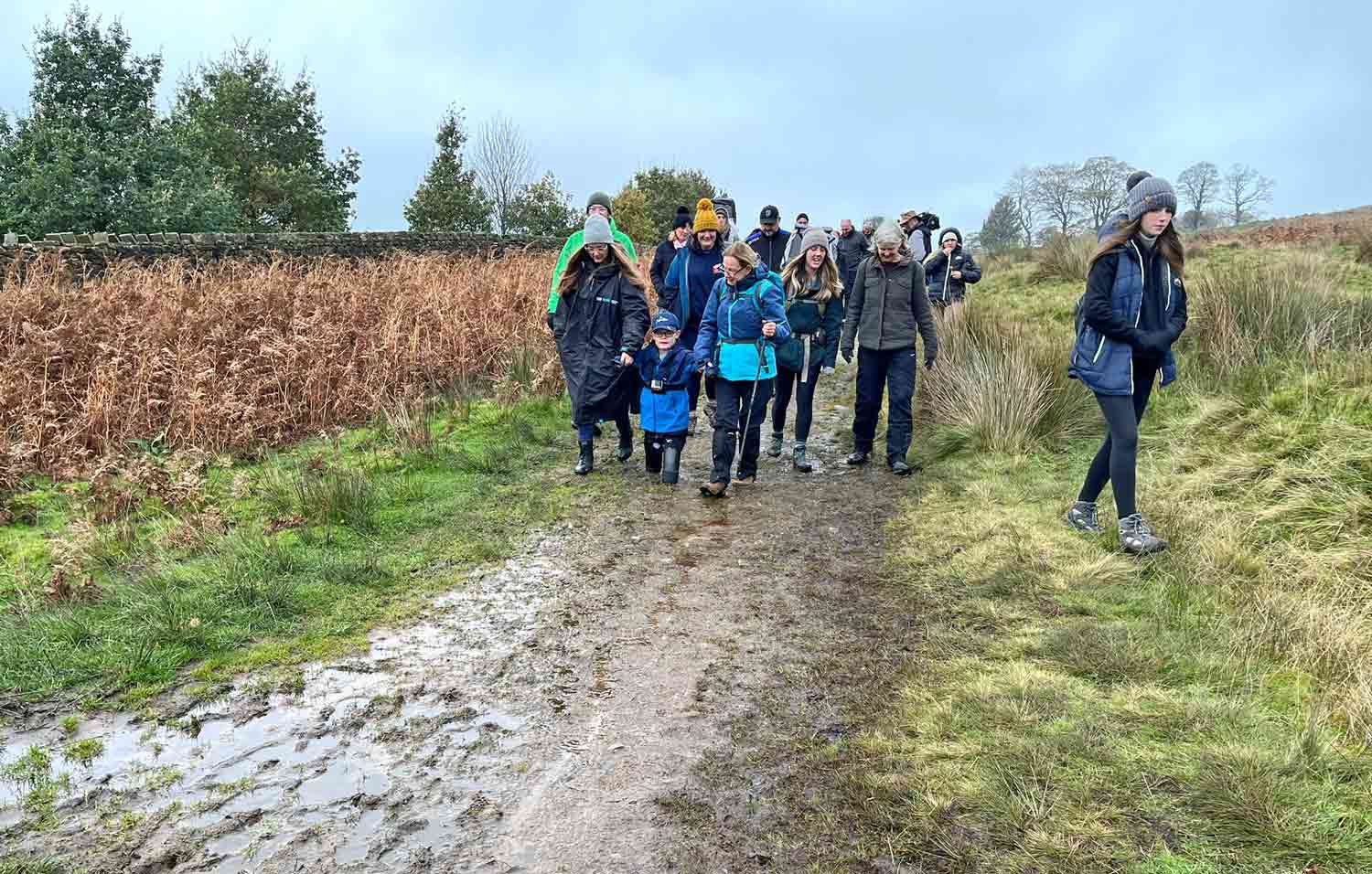 Luke Mortimer walks between two adults as he leads a group of hikers along a trail.