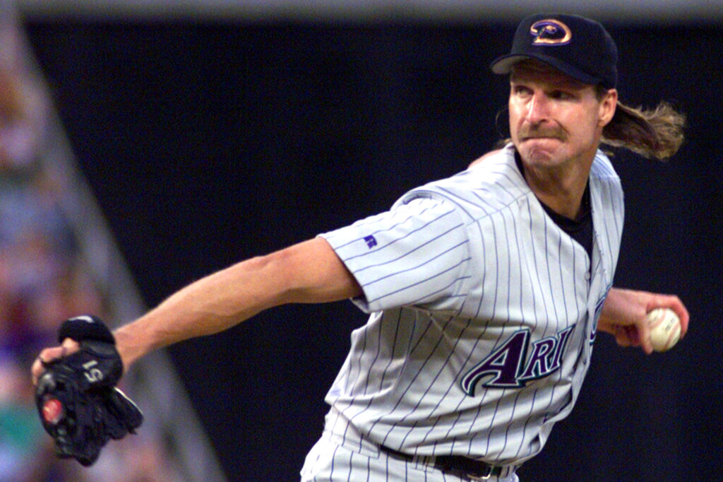Randy Johnson is poised to pitch a baseball while wearing a pinstripe uniform.
