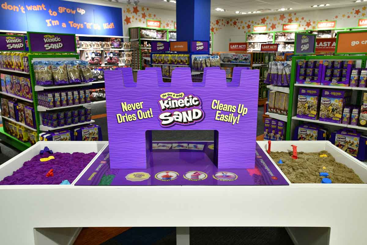 A play table containing two sections full of kinetic sand with shovels and other accessories.
