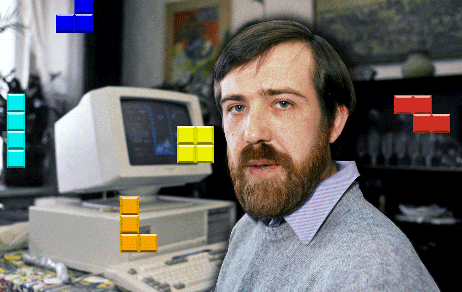 A man poses in front of a 1980s computer as digital Tetris shapes fall around him.