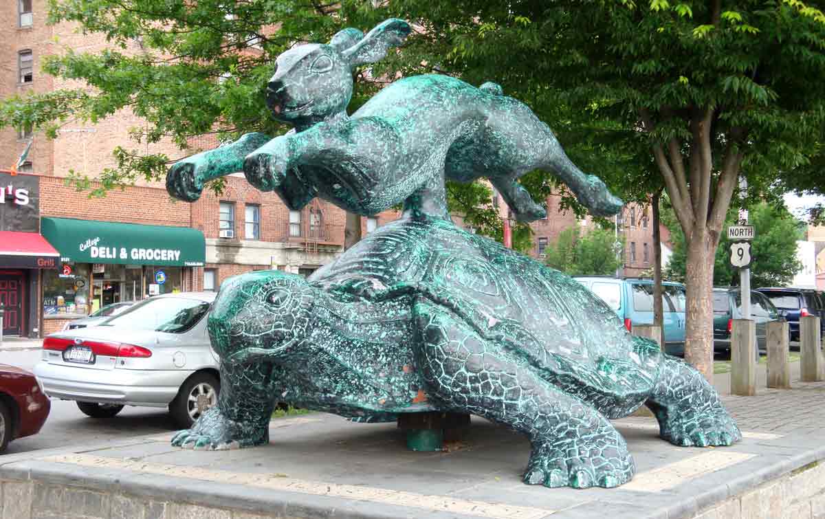An outdoor sculpture of a hare leaping over a tortoise.