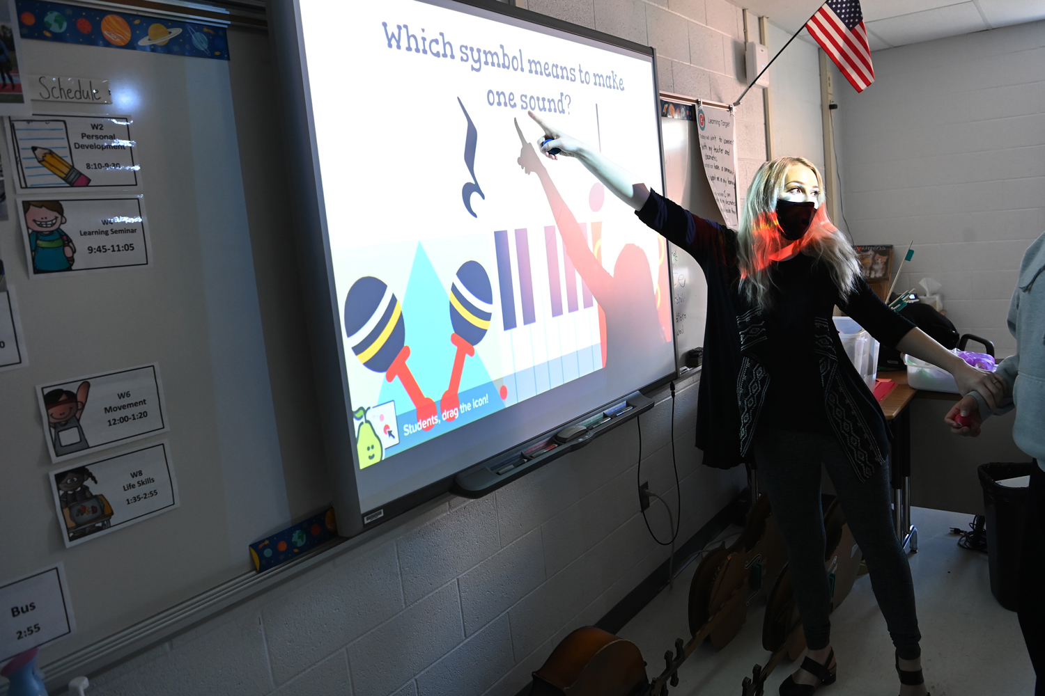 Annie Ray points to a screen that reads Which symbol is used to make one sound and shows several musical symbols.