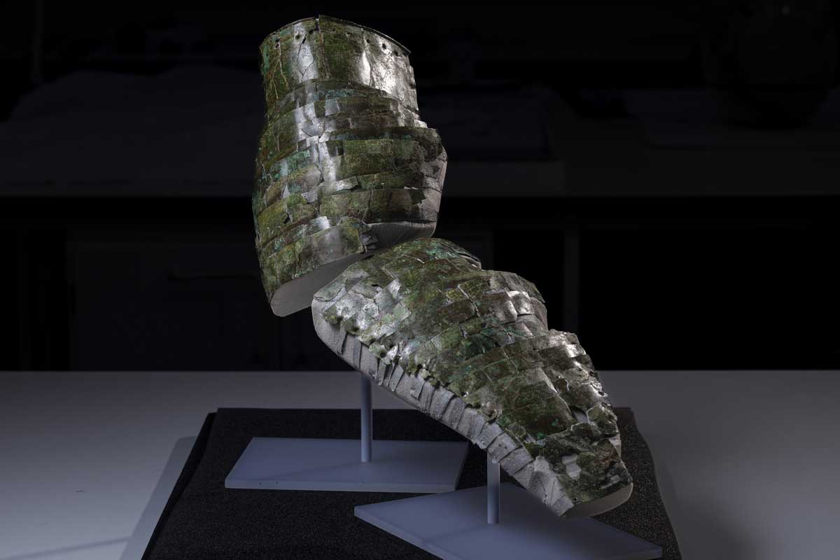 An aged ancient Roman arm guard is on display on a table.
