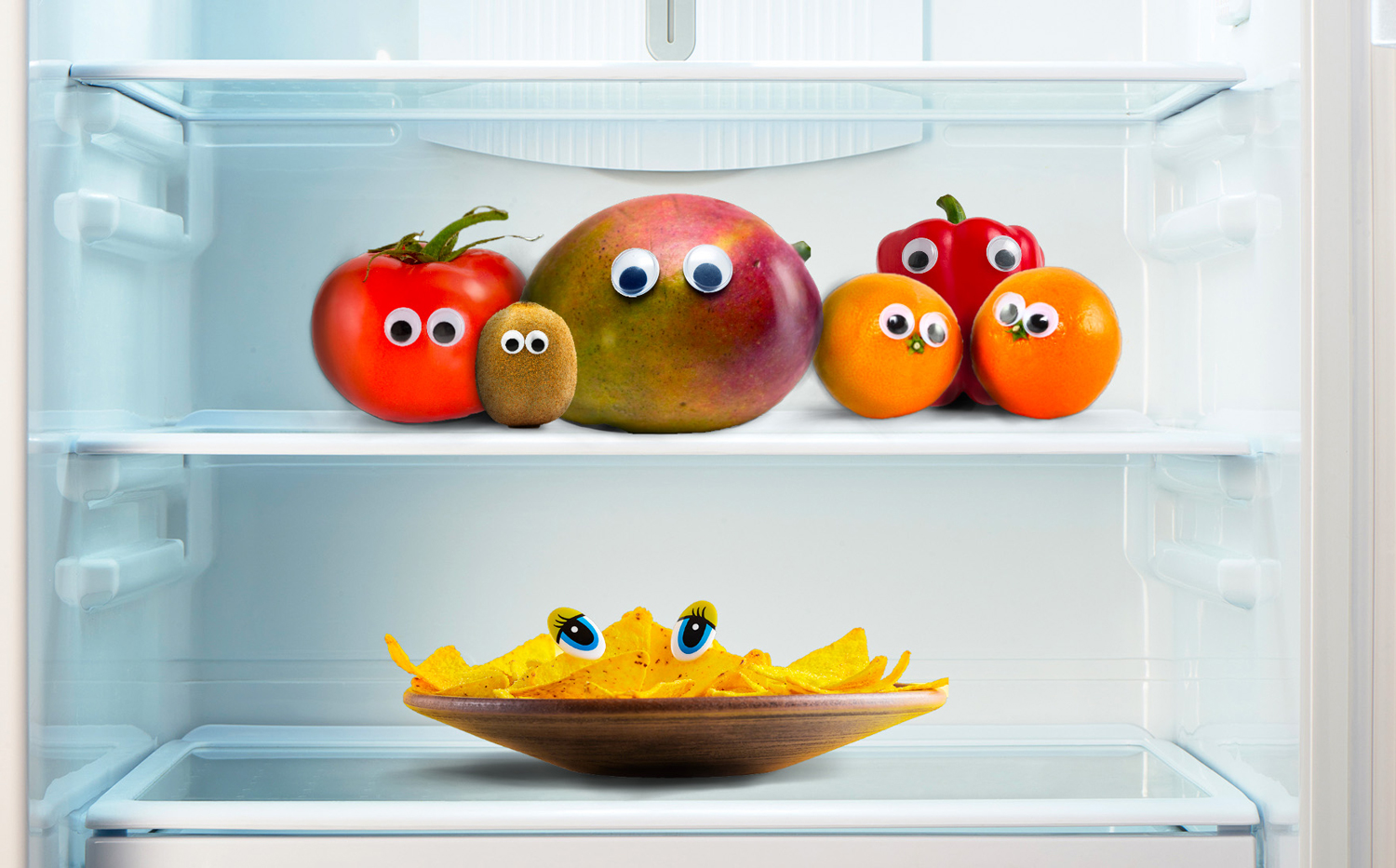 A refrigerator is full of food that has googly eyes stuck on it.