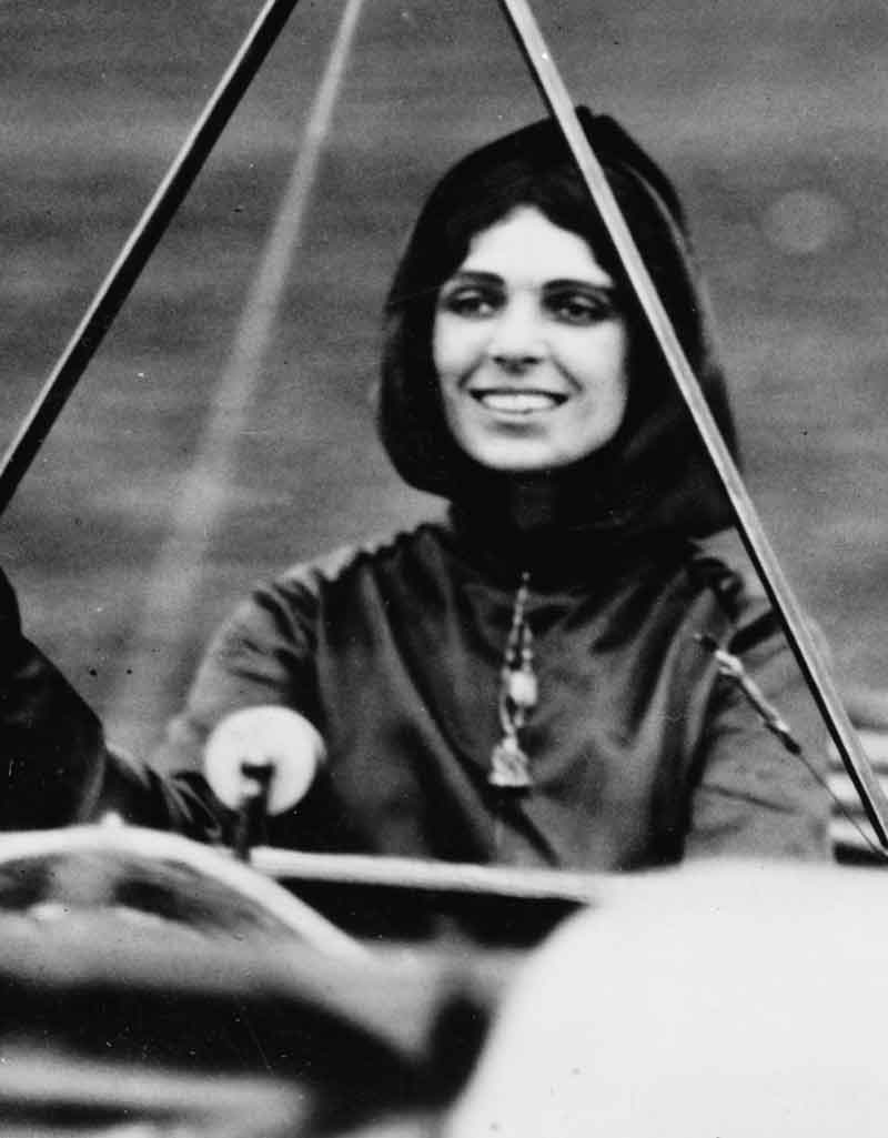 Harriet Quimby smiles while sitting in an airplane cockpit.