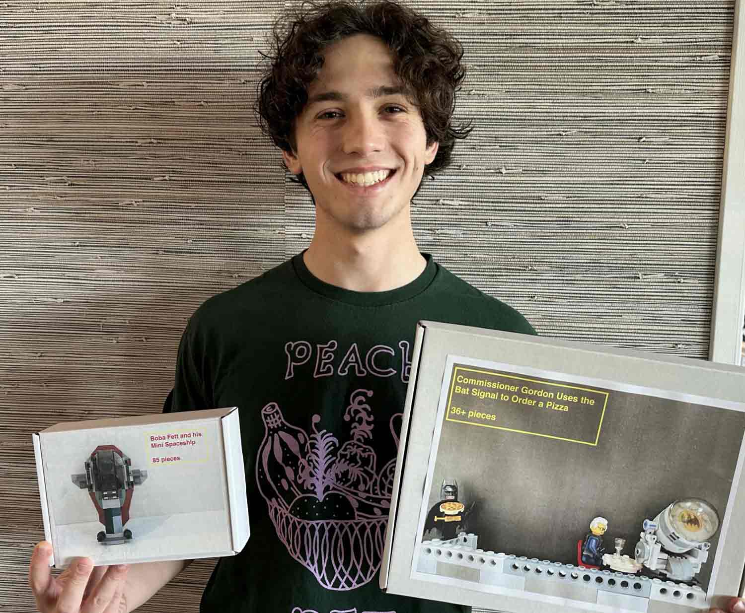 A teen holds up two boxes, each with a photo of a constructed LEGO set.