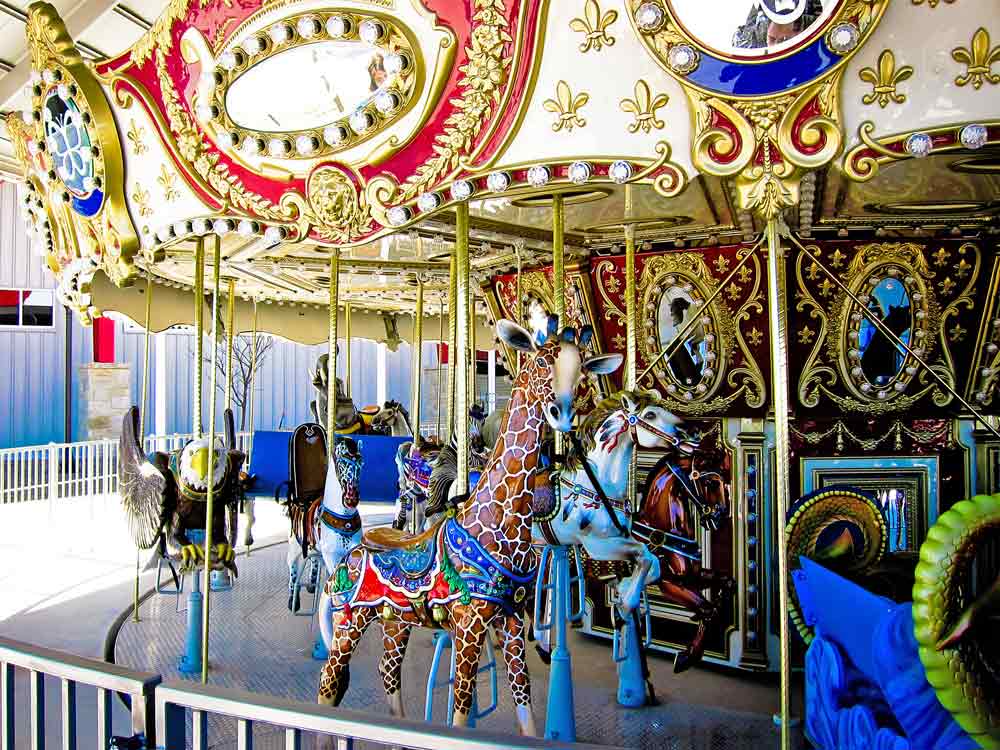 A carousel with a riding giraffe, eagle, and horses.