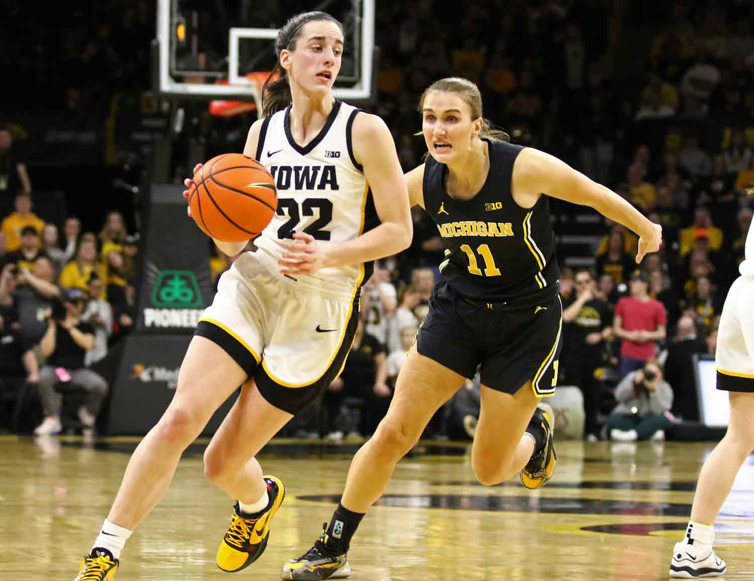 Caitlin Clark dribbles the ball during a game with an opposing player attempting to steal.