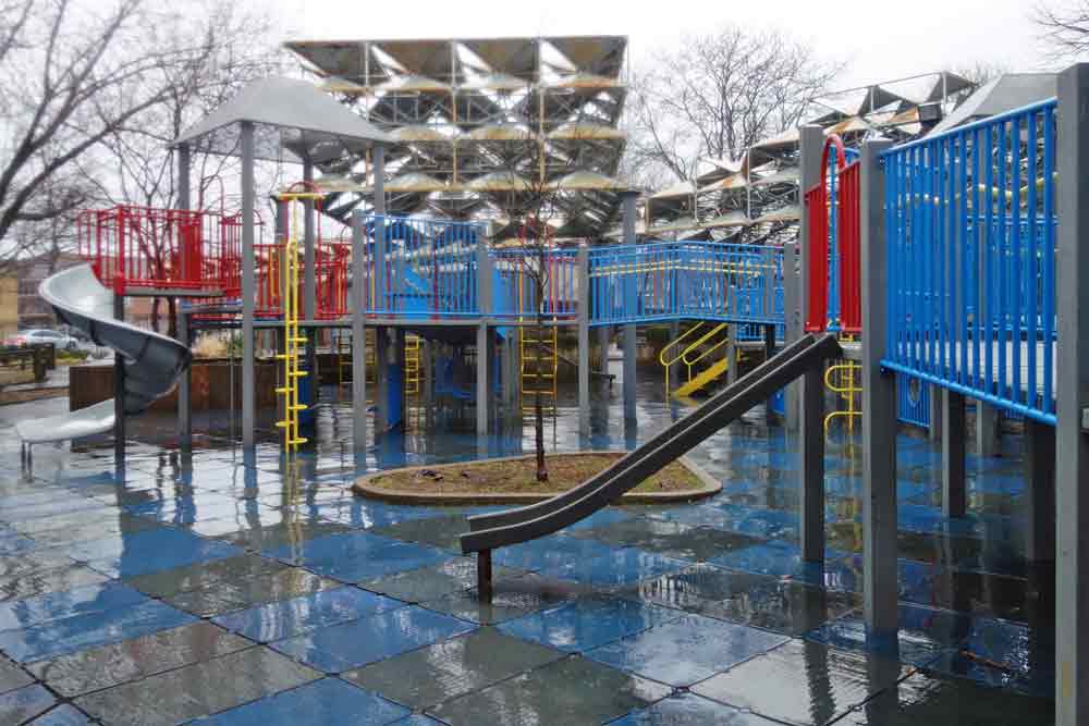 A playground area includes climbing equipment, two slides, and ladders.