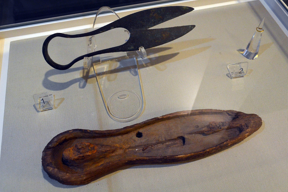 A tool resembling scissors and its carrying case are in a display case.