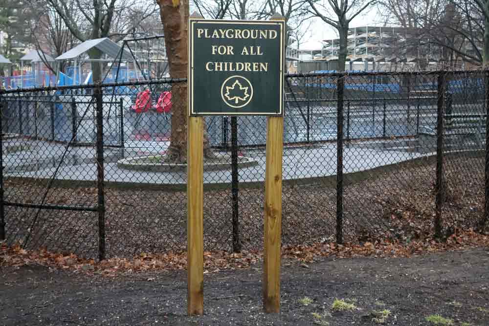 A sign is in front of an outdoor playground and reads Playground for All Children