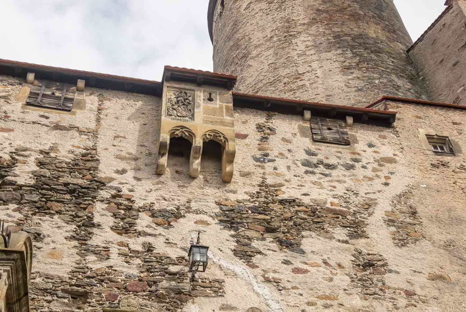 A latrine structure is built on the side of a castle wall.